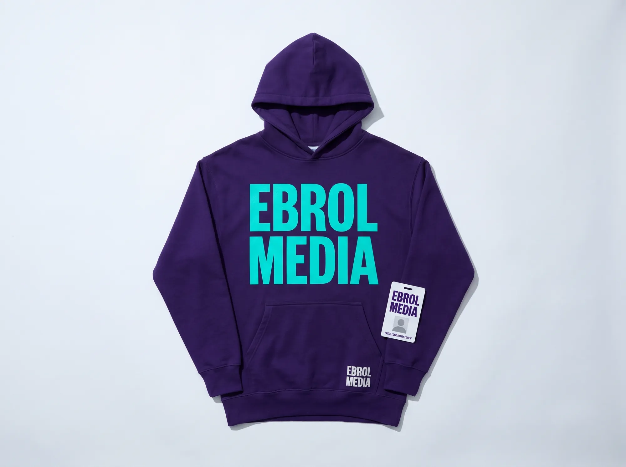 Ebrol Media Practitioner Hoodie (Apparel) — A heavyweight cotton hoodie — deep violet (#2A1240) with EBROL MEDIA printed in electric cyan (#00E5C5) Space Grotesk bold caps across the chest. Issued to working media-deployment field engineers and working customer-success engineers.